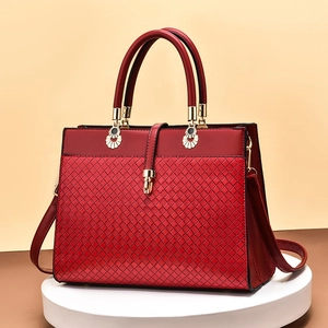 Red woven leather tote bag with gold buckle on a white stand for 2025 autumn fashion