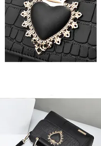 Detail of black embossed leather handbag featuring a golden heart-shaped carved buckle