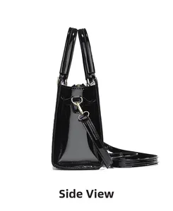 Side view of shiny black patent leather handbag with gold hardware and dual handles