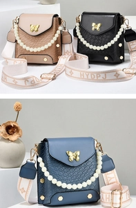 Detail of mini crossbody bag with crocodile texture, gold butterfly and pearl chain