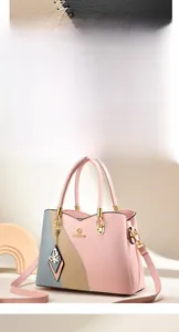 Detail of tricolor paneled soft leather handbag featuring golden logo and butterfly charm