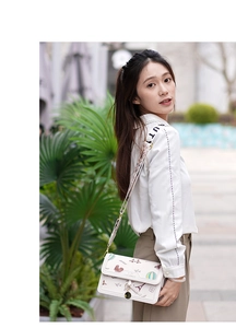 Detail of white crossbody bag with travel illustrations and wide text shoulder strap