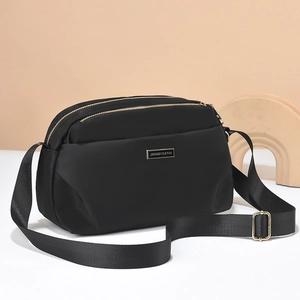 Waterproof black nylon crossbody bag for women featuring triple gold zipper compartments