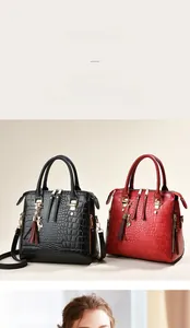 Detail of crocodile pattern handbags in black and red with gold hardware and cat charm