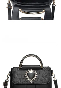 Detail of black embossed leather handbag featuring golden heart crown buckle and metal handle