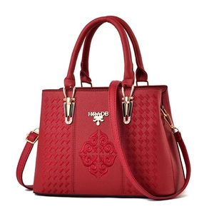 Detail of red leather handbag featuring ornate embroidery and a gold metallic logo