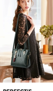 Detail of dark green crocodile texture handbag with a tassel gold cat charm detail