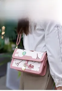 Close-up of pink crossbody bag with European landmark prints and gold logo detail