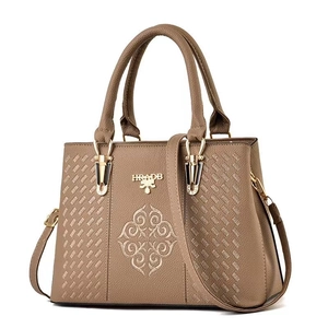 Detail of embroidery on brown lychee grain leather tote bag with gold metal logo
