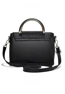 Detail of black crocodile-embossed leather handbag with metallic top handle and strap