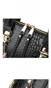 Detail of crocodile pattern bag with golden cat pendant and dual metal zippers