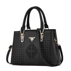 Detail of floral embroidery and gold hardware on black PU leather handbag