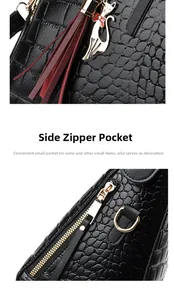Detail of black crocodile texture bag with gold zipper side pocket and red tassel charm