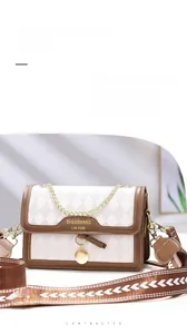 Detail of quilted leather handbag featuring brown contrast trim and wide patterned strap