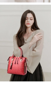 Macro view of red crocodile pattern leather bag featuring gold hardware and fringe detail
