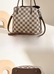 Detail view of checkerboard handbag featuring brown leather base and protective metal feet
