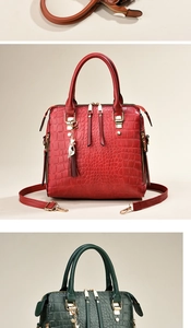 Detail of elegant crocodile-pattern leather handbag with metal cat charm and tassel