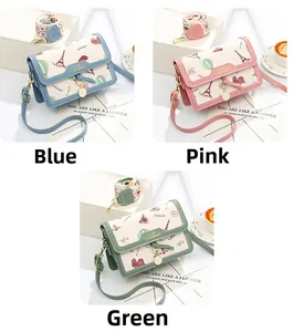 Close-up of small crossbody bags with travel-themed prints and metal pendant details