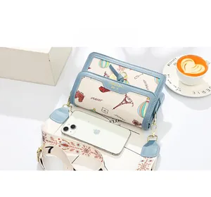 Top view of compact crossbody bag with travel print next to smartphone for size scale