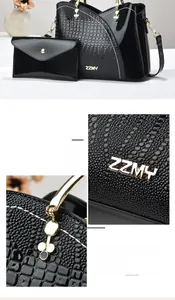 Détails de la texture crocodile et de la poignée dorée renforcée sur un sac à main noir