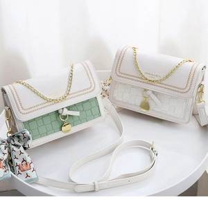 Detail of color-block flap bags with gold chain straps and floral scarf accessory
