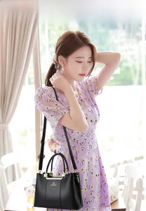 Fashionable black pebbled leather handbag with gold metal bar details and strap