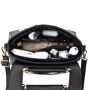 Chic black structured handbag with spacious interior compartments and gold metal handles