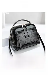 Détail du sac cabas noir motif crocodile avec fermetures dorées et texture brillante