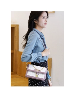 Detail of quilted crossbody bag with purple flap and gold chain on model in natural setting