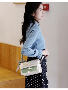 Detail of sage green crossbody bag with woven texture, gold chain and floral scarf handle