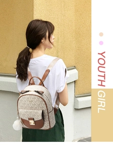 Detail view of stylish patterned backpack with leather trim and decorative fur ball charm