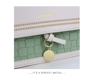 Detail of cream leather bag with green checkered embossing, floral embroidery and gold logo