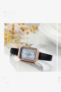 Detail of rose gold rectangular watch with blue textured dial and black leather strap