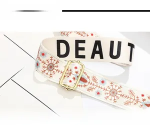 Detail of wide woven shoulder strap with blue snowflake patterns and gold metal buckle