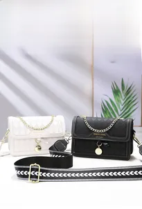 Detail view of black and white quilted crossbody bags with wide patterned straps and gold chains