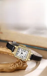 Detailed macro view of vintage square watch with gold case and black leather strap