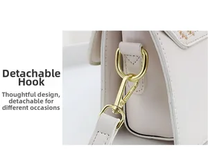 Detail of white leather handbag featuring gold hardware and detachable metal carabiner hook