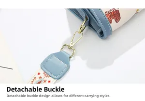 Detail of light blue crossbody bag featuring gold metal clip and printed shoulder strap
