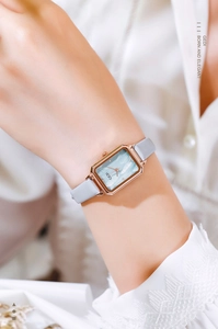 Elegant rectangular rose gold watch with blue dial and grey leather strap on model wrist