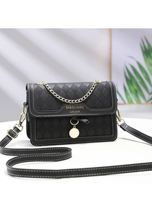 Detail of black quilted shoulder bag with gold chain strap and metal pendant charms