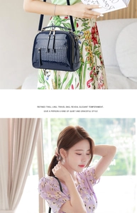 Détail d'un sac à main bleu foncé en cuir verni à motif crocodile avec double fermeture