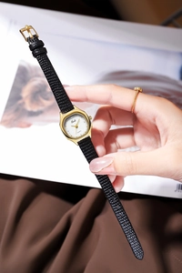 Close-up of Gedi quartz watch featuring a small square white dial and black leather strap