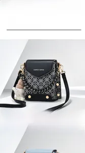 Detail of black crossbody phone bag with vintage pattern, chain strap and white fur ball