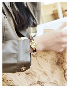 Close-up of vintage oval gold watch with brown leather strap on model wrist