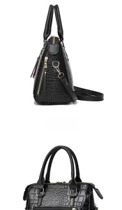 Detailed side view of black crocodile pattern tote bag with gold hardware and tassel charm
