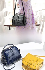 Détail du sac à bandoulière brillant avec relief crocodile et double fermeture éclair