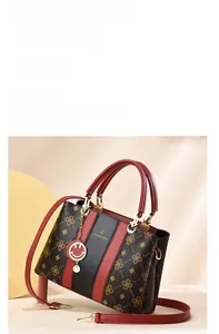 Détail du sac cabas rouge et noir avec motif trèfle et pendentif smiley brillant