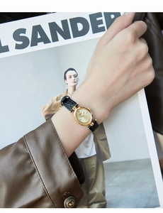 Close-up of vintage oval quartz watch with black leather strap on female wrist
