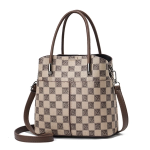 Vintage checkered tote bag with leather trim and adjustable crossbody strap on white background
