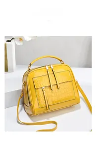 Détail macro du sac à main jaune verni avec texture gaufrée crocodile et finitions soignées